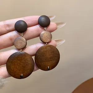 Macro detail of retro triple-layered wooden geometric dangle earrings in earthy brown tones