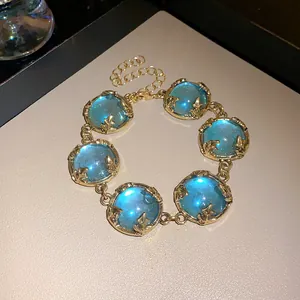 Close-up of vintage gold bracelet with large blue resin stones and leaf claws