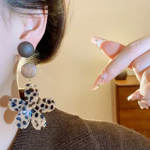 Close-up of vintage leopard print flower earrings with wooden studs worn on an ear