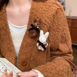 Close-up of cute plush rabbit brooches with velvet bows on a brown sweater