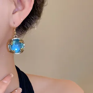 Detailed close-up of a vintage resin earring featuring a blue orb and gold leaf accents