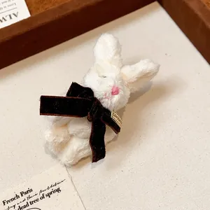 Detailed view of a cute white plush rabbit brooch with a brown velvet ribbon bow