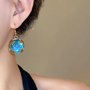 Close-up detail of vintage court style blue resin earring with ornate gold frame