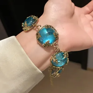 Detailed view of a vintage court style gold-toned bracelet with large blue resin stones