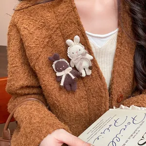 Close-up of cute white and brown flocked bunny brooches pinned on a cozy brown cardigan
