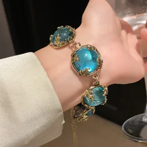 Close-up of vintage gold bracelet with square blue resin stones on wrist.