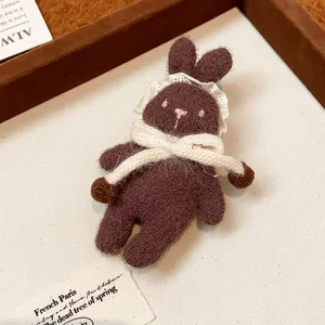 Close-up of a brown flocked rabbit brooch with lace collar and bow detail