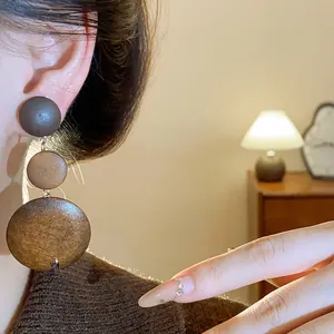 Detailed close-up view of vintage brown tiered wooden drop earrings in Maillard style