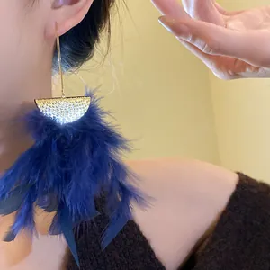 Close-up detail of luxury deep blue feather tassel earrings with golden textured metal