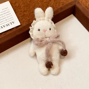 Close-up of a cute handmade knit white rabbit brooch with lace collar and bow