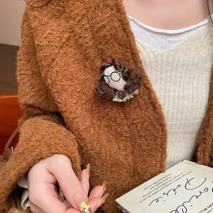 Close-up of creative doll head brooch with glasses on a brown knit sweater