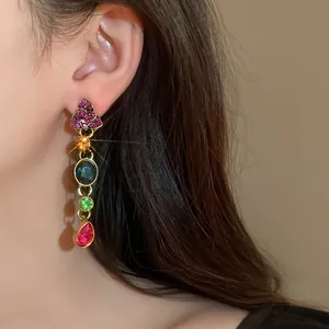 Detalle de pendientes colgantes vintage de estilo corte con piedras de varios colores