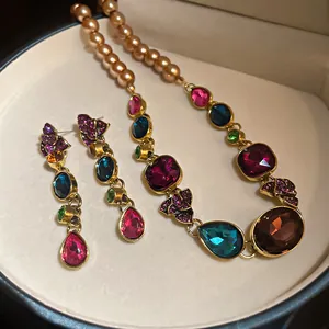 Primer plano de un conjunto de joyas vintage con gemas de colores y perlas estilo corte.