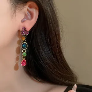Primer plano de pendientes colgantes vintage con pedrería de colores en una oreja