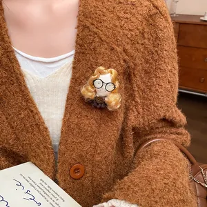 Detailed view of a cute handmade fabric doll brooch on a warm brown knitted cardigan.