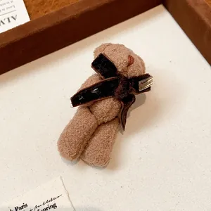 Close-up detail of a brown flocked bear brooch featuring a dark velvet bow accent