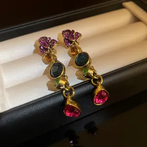 Primer plano de pendientes vintage con piedras preciosas de colores en caja de regalo negra