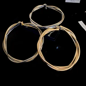 Close-up of intertwined multi-strand metallic necklaces in gold and silver finish on black background
