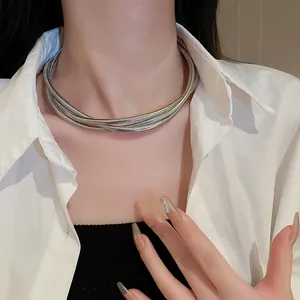 Detail view of a stylish multi-layer silver coiled snake chain necklace on model.