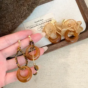 Close-up detail of vintage amber resin drop earrings and mesh flower studs in warm tones.
