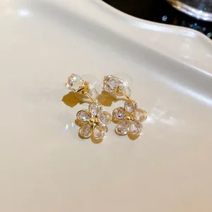 Close-up macro view of elegant flower dangle earrings with clear sparkling crystals and gold finish