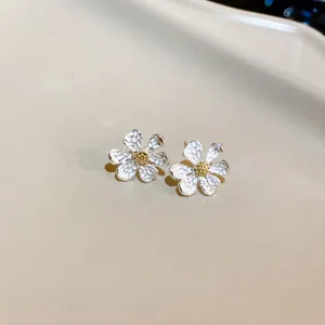 Macro shot of elegant floral stud earrings featuring silver textured petals and gold center