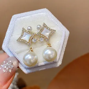 Elegant 14K gold plated star stud earrings with white pearls and zircon accents on a white box