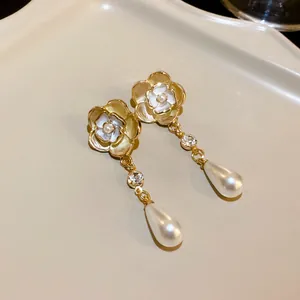 Elegant camellia flower earrings with pearl and crystal drop details on a cream tray
