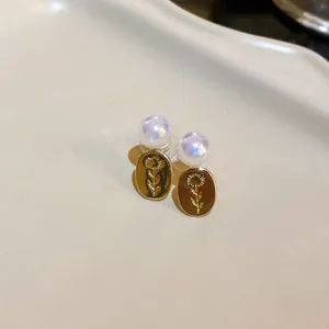 Detailed macro view of vintage gold oval flower earrings featuring iridescent pearl beads