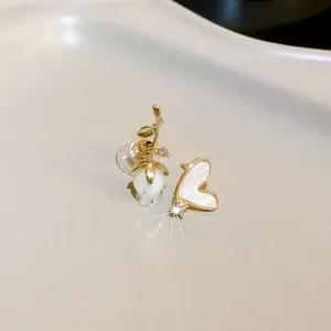 Close-up of asymmetric vintage gold earrings with pearl flower and shell heart design