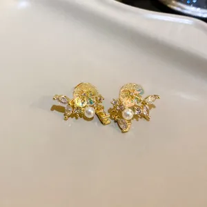 Close-up macro view of vintage floral stud earrings featuring pearls and iridescent crystals
