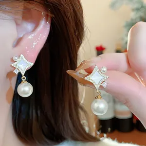 Close-up detail of 14K gold plated star stud earrings featuring zircons and elegant pearl drops