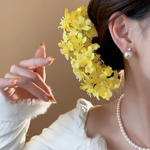 Detailansicht einer leuchtend gelben Stoffblumen-Haarnadel an einer eleganten Frisur