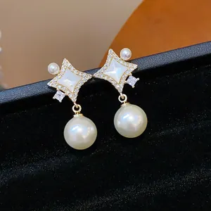 Elegant four-pointed star earrings with central white stone and dangling pearls detail