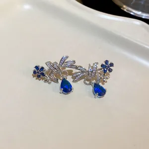 Detailed view of silver bow earrings featuring blue crystals and teardrop pendants.