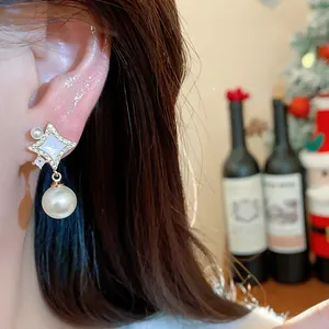 Close-up of 14K gold-plated star earrings featuring white shell, zircon, and pearl