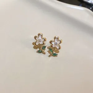 Close-up detail of vintage flower earrings featuring green stone leaves and white petals