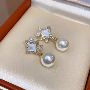 Macro detail of 14K gold plated star earrings featuring zircons and elegant dangling pearls