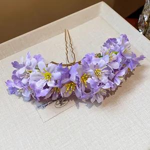 Detailansicht einer eleganten goldenen Haarnadel mit lila Stoffblumen für Damen