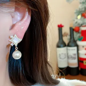 Close-up detail of 14K gold plated star stud earring with a dangling pearl on model ear