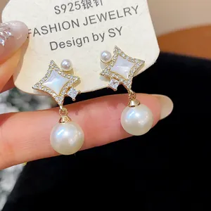 Close-up detail of 14K gold plated star earrings with zircons and elegant drop pearls