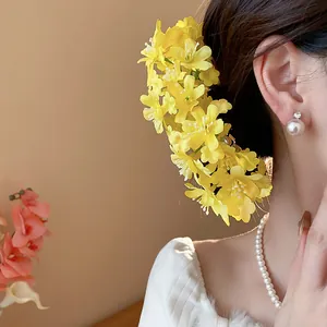 Makro-Detail einer süßen gelben Stoffblumen-Haarnadel getragen von einer Frau