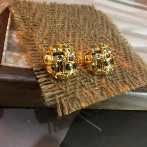 Primer plano de pendientes redondos dorados de estilo vintage en fondo de arpillera.
