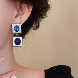 Gros plan détaillé de boucles d'oreilles vintage argentées avec gemme bleue et cabochon.