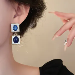 Gros plan sur des boucles d'oreilles carrées de style vintage avec pierres bleues