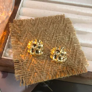 Vista detallada de pendientes vintage dorados con textura trenzada sobre fondo de arpillera