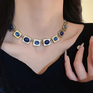 Gros plan d'un collier vintage doré avec pierres bleues porté par un mannequin