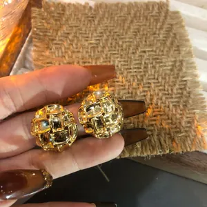 Vista detallada de pendientes de botón tejidos dorados vintage con acabado brillante