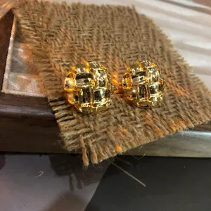 Vista de detalle de pendientes de botón redondos dorados con textura de tejido