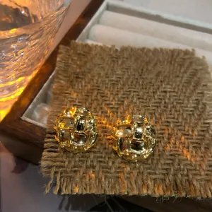 Vista detallada de pendientes de botón retro dorados con textura tejida irregular